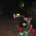 Auf der Straße in Mini-Plastikstühlen essende Chinesen